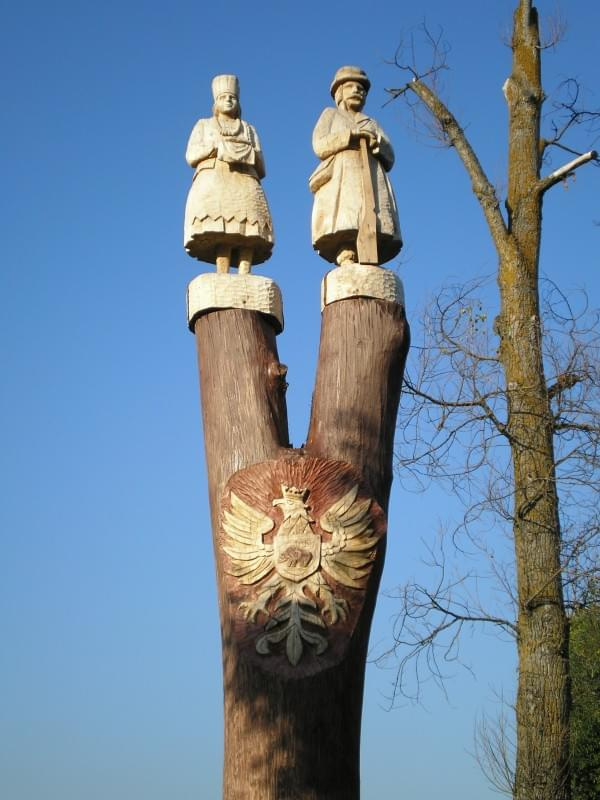 Te figurki sa w Ostrołęce,a na tym drzewie znajduje się para kurpiowska,a na srodku jest godło Ostrołęki.:)
