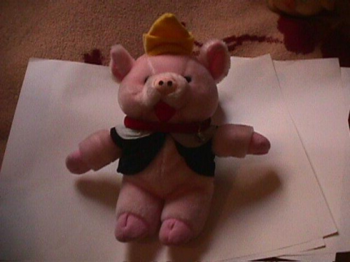 różowa świnka w smokingu z dzwoneczkiem na szyi w żółtym kapelusiku